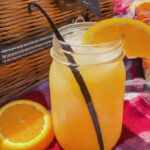 Orange Dreamsicle Moonshine in a mason jar with orange slice and vanilla bean.