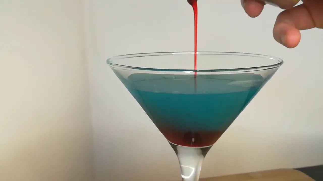Pouring grenadine into the Shark Bite drink to create blood effect.